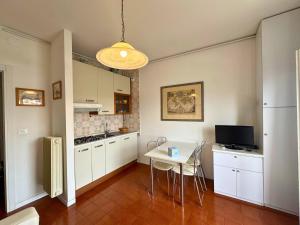 a kitchen with white cabinets and a table with chairs at Riviera Appartament in Grado