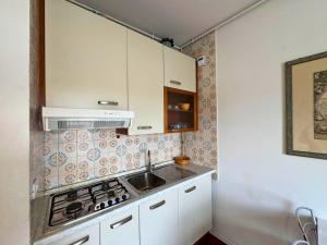 a small kitchen with white cabinets and a sink at Riviera Appartament in Grado +11 photos