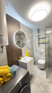 a bathroom with a sink and a toilet and a mirror at APARTAMENT Nowoczesny PRL in Bydgoszcz