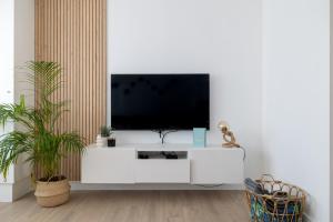 a living room with a tv on a white cabinet at Warvinge 73 in De Haan