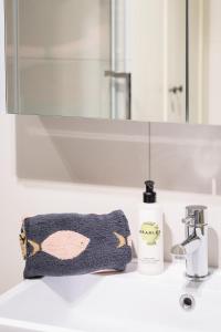 a bathroom sink with a towel and a bottle of soap at Modern Flat on the seafront Exmouth in Exmouth +24 photos