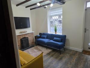 a living room with a blue couch and a fireplace at The Indigo Escape in Ibstock