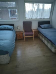 a bedroom with two beds and a chair and a window at Cristabel Guest House in Clacton-on-Sea
