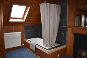 a bathroom with a bath tub with a shower curtain at The Loan in Achiltibuie +43 photos
