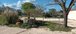 an empty playground with a tree and a swing at Gîte L'Olivier - Piscine partagée in Lagorce