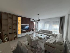 a living room with a couch and chairs and a tv at Eda's Home in Mitrovica
