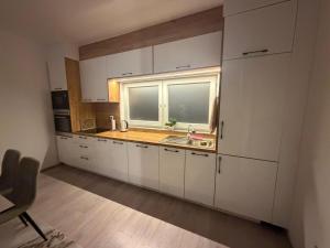 a kitchen with white cabinets and a sink and a window at Eda's Home in Mitrovica