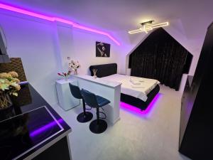 a room with a bed and a table with purple lights at Luxury Central Studio in Craiova +2 photos