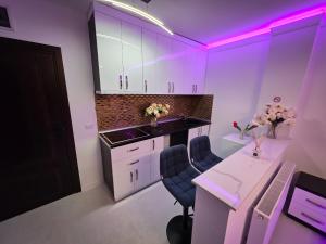 a kitchen with purple lighting and a desk and chairs at Luxury Central Studio in Craiova