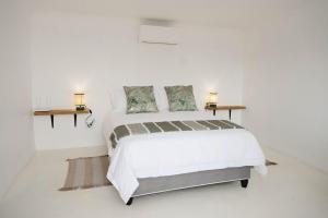 a white bedroom with a large bed and two tables at Landskap in Robertson