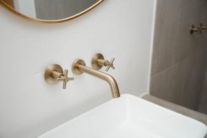 a bathroom sink with a gold faucet and a mirror at Landskap in Robertson