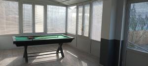 a room with a pool table in front of windows at Gîte L'Olivier - Piscine partagée in Lagorce