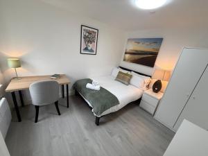a small bedroom with a bed and a desk and a table at Sleek 1BR Flat Perfect Getaway For Contractors Or Couples in Cardiff