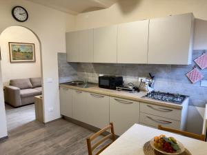 a kitchen with white cabinets and a table and a couch at Casa Falconcini in Volterra