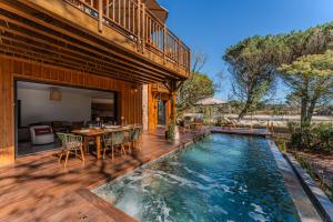 a house with a swimming pool on a wooden deck at Villa Saint Brice, frontline in Arès