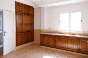 a kitchen with wooden cabinets and a window at Résidence Mestaoui in Houmt Souk