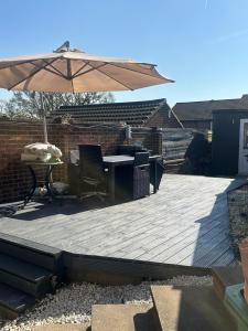 a wooden deck with a table and an umbrella at M18 Escape in Havering atte Bower