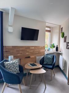 a living room with two chairs and a table and a tv at Au fil de l’Ô in Bisseuil
