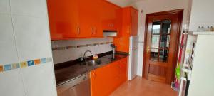 a kitchen with orange cabinets and a sink at Apartamento Mar in Bádames