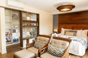 a bedroom with a bed and two chairs at Refúgio das Galés Mariscal in Bombinhas
