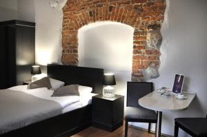 sypialnia z łóżkiem, stołem i ceglaną ścianą w obiekcie Krakow For You Main Square Apartments w Krakowie