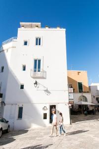 two people walking in front of a white building at Monsignore Luxury Suite in Monopoli