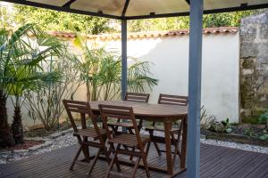 a wooden table and chairs under an umbrella on a deck at Maison de ville Libourne 3 chambres in Libourne