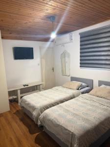 two beds in a room with a desk and a tv at Hostel FM in Mostar
