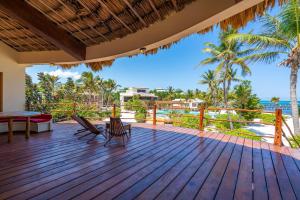 a deck with chairs and a table on the beach at La Perla del Caribe - Villa Opal in San Pedro