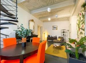 a living room with a table and orange chairs at DUPLEX DE CHARME XVIIIᵉ - TERRASSE Privée - Centre Historique - HALLES GARE - Tout à Pied - RétroMirabeau Le Jacobin in Narbonne