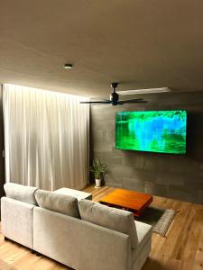 ein Wohnzimmer mit einem weißen Sofa und einem Fernseher in der Unterkunft HighLand 伊豆大島箱根連峰を望む高級貸切ヴィラサウナ大型ウッドデッキ薪ストーブ完備 in Arashi