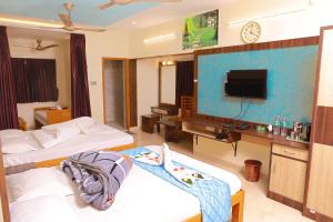 a hotel room with two beds and a tv at Bhavan Resorts in Yercaud