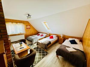 a room with two beds and a table and chairs at Pokoje U Rycha in Augustów