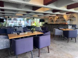 a restaurant with wooden tables and purple chairs at Hotel Las Pergolas in Guadalajara