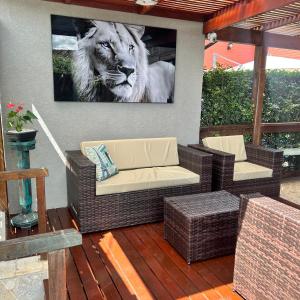 a patio with two wicker chairs and a picture of a lion at Chalé com PISCINA Privativa, com 2 QUARTOS, ESTACIONAMENTO em Condomínio com PORTARIA 24h, Sauna, Quadras, 3 PISCINAS no condomínio, Pesca e Parquinho Infantil - SmarTV na sala de estar, TV na área CHURRASQUEIRA, Wi-Fi e Cozinha Completa in Atibaia +110 photos