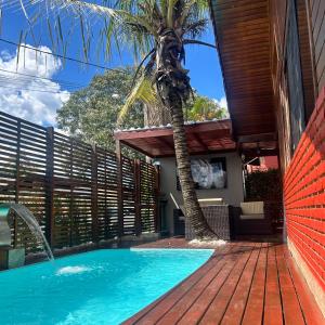 a swimming pool with a palm tree next to a house at Chalé com PISCINA Privativa, com 2 QUARTOS, ESTACIONAMENTO em Condomínio com PORTARIA 24h, Sauna, Quadras, 3 PISCINAS no condomínio, Pesca e Parquinho Infantil - SmarTV na sala de estar, TV na área CHURRASQUEIRA, Wi-Fi e Cozinha Completa in Atibaia