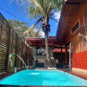 a swimming pool with a palm tree next to a house at Chalé com PISCINA Privativa, com 2 QUARTOS, ESTACIONAMENTO em Condomínio com PORTARIA 24h, Sauna, Quadras, 3 PISCINAS no condomínio, Pesca e Parquinho Infantil - SmarTV na sala de estar, TV na área CHURRASQUEIRA, Wi-Fi e Cozinha Completa in Atibaia