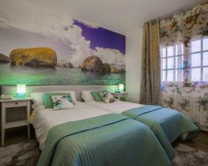 ein Schlafzimmer mit einem Bett und einem Gemälde an der Wand in der Unterkunft Hotel & Apartamentos Cons da Garda in San Vicente de O Grove + 60 Fotos