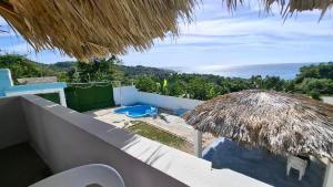a view of the ocean from a house with a straw umbrella at Villa hotel Gabi Larimar in La Ciénaga
