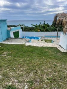 a house with a yard with a pool and the ocean at Villa hotel Gabi Larimar in La Ciénaga