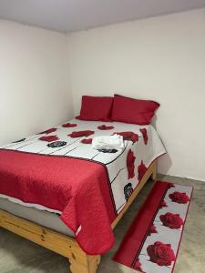 a bed with a red and white blanket and red pillows at Villa hotel Gabi Larimar in La Ciénaga