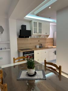 a kitchen with a dining table and a kitchen with white cabinets at Fier Glass Apartament in Fier