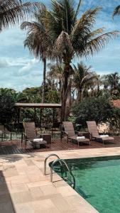 a swimming pool with two chairs and a palm tree at Pousada Recanto da Grande Paz in Alto Paraíso de Goiás