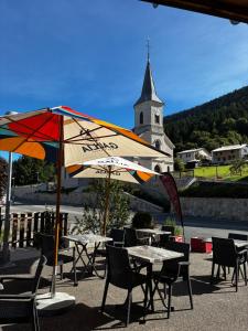 a group of tables and chairs with an umbrella at Hôtel du Centre - Restaurant Lelex'ir in Lélex