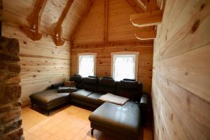 a living room with leather furniture in a log cabin at Ferienhaus Fließ Paradies mit privatem Saunahaus - Leipe, Spreewald in Leipe