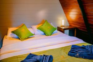 a bed with two green pillows on top of it at Brilliant View Cottages in Ella