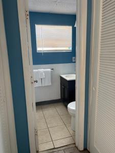 a blue bathroom with a toilet and a window at OCEANS 735 of DEERFIELD BEACH in Deerfield Beach