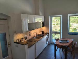 a kitchen with white cabinets and a table and a sink at Scaglie di Mare in Manarola