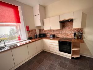 a kitchen with white cabinets and a sink and a window at Home in Dunoon Argyll and Bute in Dunoon