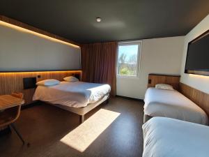 a hotel room with two beds and a window at B&B HOTEL Clermont-Ferrand Nord Riom in Riom